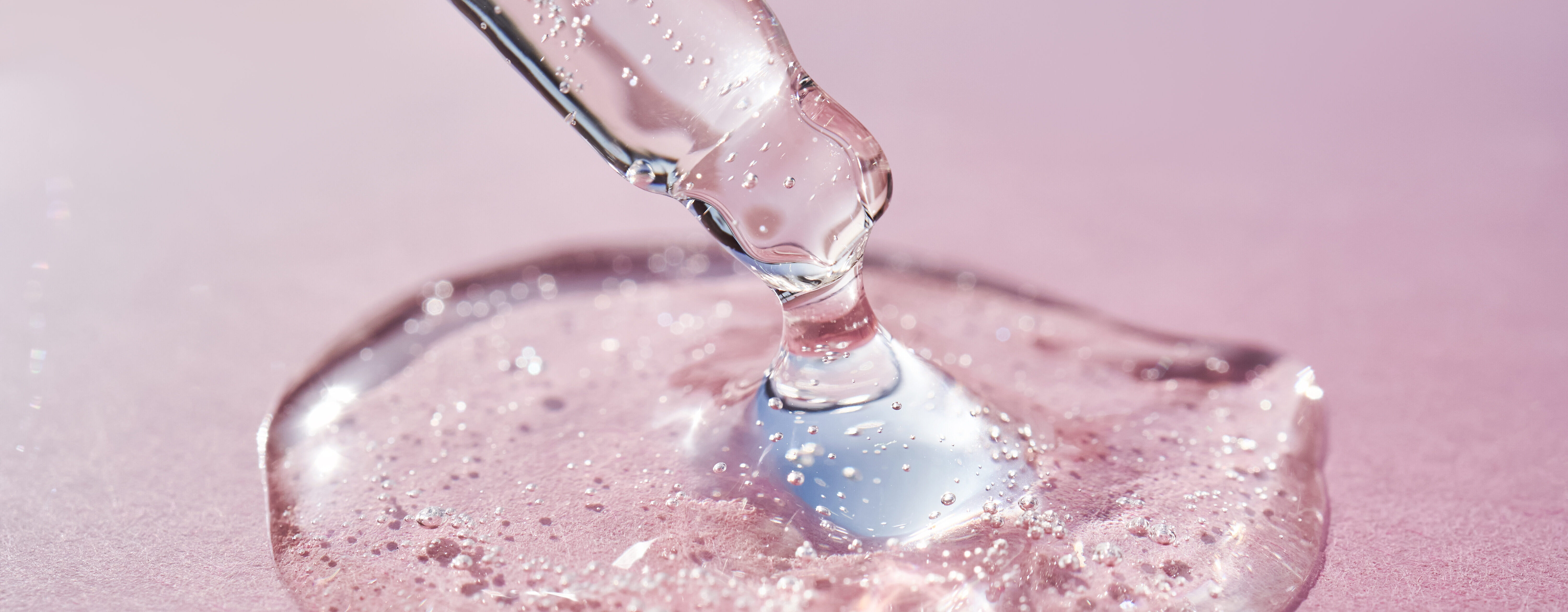 Pipette with serum shimmering in the sun on a pink background. Pipette with serum shimmering in the sun on a pink background. High quality photo.